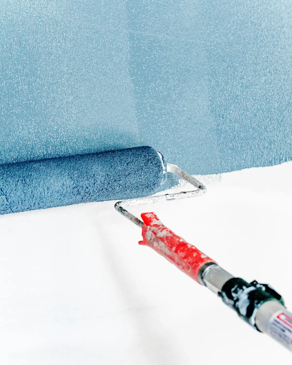 A paint roller on a pale blue wall.