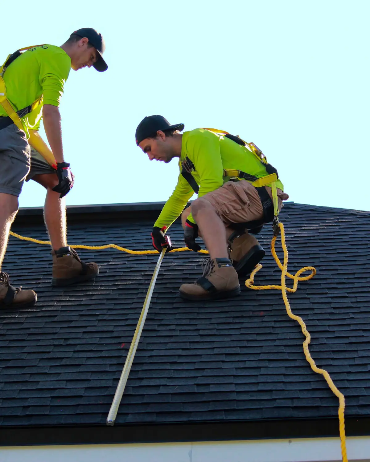 Two people measuring a tiled roof.